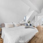 Schlafzimmer mit Dachschräge, Bett, Nachttisch und Lampe.