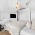 Schlafzimmer mit Bett, Schrank und Fernseher an der Wand.