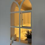Blick durch ein Fenster auf eine Badewanne und eine Pflanze.
