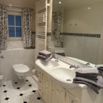Badezimmer mit Waschbecken, Spiegel, Toilette und Fenster mit Vorhängen.
