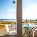Balcony with table and chairs overlooking the sea and beach.