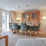 Esszimmer mit Holztisch, Stühlen und Sideboard. Lichtdurchfluteter Raum mit Holzboden.