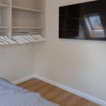 Schlafzimmer mit Kleiderschrank und Wandfernseher