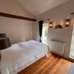 Schlafzimmer mit Holzboden, Bett, Fenster und Wandleuchten.