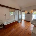 Badezimmer mit Badewanne, Dusche und Holzboden.