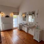 Badezimmer mit zwei Waschbecken, Spiegeln und Holzboden