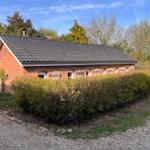Rotes Backsteinhaus mit Dach und Hecken. Garten mit Kiesweg.