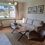 Wohnzimmer mit Sofa, Stuhl, Tisch und Fenster. Wandbilder und Teppich.