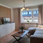 Wohnzimmer mit Sofa, Couchtisch und Fernseher an Holzwand