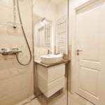 Badezimmer mit Dusche, Waschbecken und Heizkörper