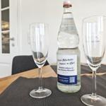 Auf dem Tisch stehen zwei Gläser und eine Flasche Mineralwasser.