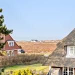 Haus mit Strohdach und rotem Dach, Blick auf Felder und Ferienhäuser