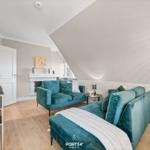 Wohnzimmer mit zwei türkisfarbenen Sofas, Kamin und Holzboden.