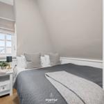 Schlafzimmer mit Dachschrägen, Bett, Nachttisch und Fenster.