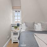 Schlafzimmer mit Dachschrägen, Fenster und Bett mit Kissen.