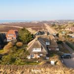 Dorf mit strohgedeckten Häusern und Blick auf die Nordsee.