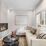 Wohnzimmer mit Ecksofa, Kamin und runden Tisch.