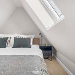 Schlafzimmer mit Dachschrägen, Dachfenster, Bett und Nachttisch.