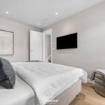 Schlafzimmer mit Bett, Wandbild, TV und Sitzhocker.