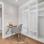 Schlafzimmer mit Kleiderschrank und Schreibtisch mit Stuhl und Lampe.