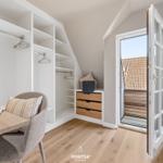 Schlafzimmer mit Kleiderschrank, Schreibtisch und Balkontür.