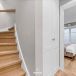 Holztreppe führt zur Schlafzimmer-Ecke mit Bett und Fenster.