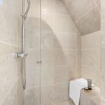 Dusche mit Duschbrause und Handbrause, hell verkleidet mit Steinplatten.
