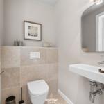 Badezimmer mit Toilette, Waschbecken und Spiegel. Wandverkleidung aus Stein.