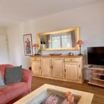 Ein Wohnzimmer mit rotem Sofa, Holzmöbeln und Fernseher.