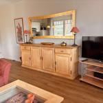 Ein Wohnzimmer mit Holzmöbeln, Fernseher und Spiegel an der Wand.