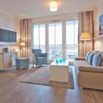 Wohnzimmer mit Sofa, Sessel und Balkonansicht