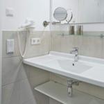 Badezimmer mit Waschbecken, Spiegel und Handtuchhalter.