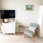 Ein Raum mit Fernseher, Schrank, Stuhl und Bild an der Wand.