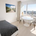 Zimmer mit Bett, Esstisch und Blick auf die Stadt.