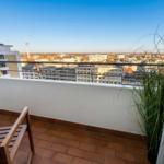Terrasse mit Holzmöbeln und Blick auf die Stadt