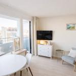 Wohnung mit Essbereich, TV und Sitzgelegenheit. Große Fenster mit Blick auf die Stadt.