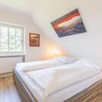 Schlafzimmer mit Doppelbett, Fenster und Wandbild.