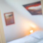 Schlafzimmer mit Bett, Wandbildern und warmem Licht.