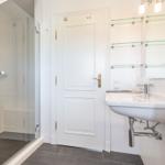 Badezimmer mit Dusche, Waschbecken und Spiegelschrank.