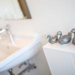 Badezimmer mit Waschbecken und drei dekorativen Entenfiguren auf Schrank.