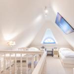 Zimmer mit Dachschrägen, Bett, Schreibtisch und Fernseher.