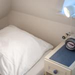 Schlafzimmer mit Bett, Nachttisch und Lampe an Fensterbank