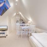 Schlafzimmer mit Doppelbett, Esstisch und Fernseher unter Dachschrägen.