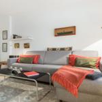 Ein Wohnzimmer mit grauem Sofa, rotem Decken und schwarzer Couchtisch.