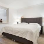 Schlafzimmer mit Bett, Nachttisch und Fenster mit Jungenfigur.