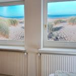 Zwei Fenster mit Blick auf Strand und Dünen.