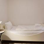 Ein Bett mit weißer Bettwäsche und Handtüchern, daneben ein Nachttisch mit Lampe.