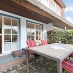 Terrasse mit Tisch und Stühlen vor einem Haus mit Dach aus Stroh
