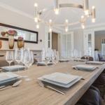 Esszimmer mit langem Holztisch, Stühlen und moderner Deckenleuchte.