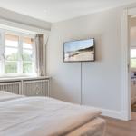Schlafzimmer mit Doppelbett, TV und Blick auf grüne Landschaft.